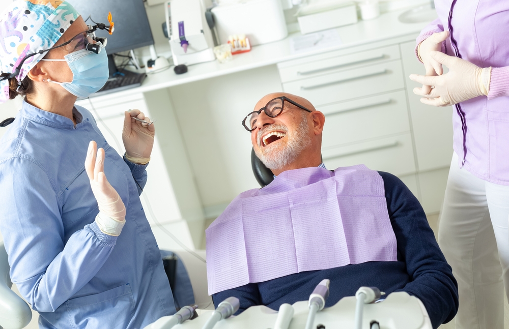 Smiling woman looking in the mirror after receiving her porcelain veneers. No text on image.