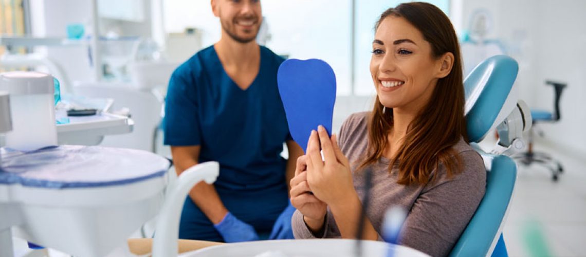 2024-08-Np1-Happy-woman-looking-her-teeth-in-a-mirror-at-dentists-office