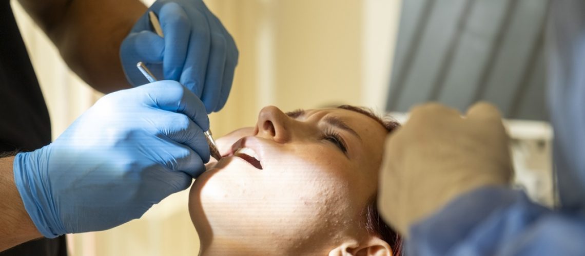 Image of a dentist in a bright office explaining options to a smiling patient, including a pamphlet titled 