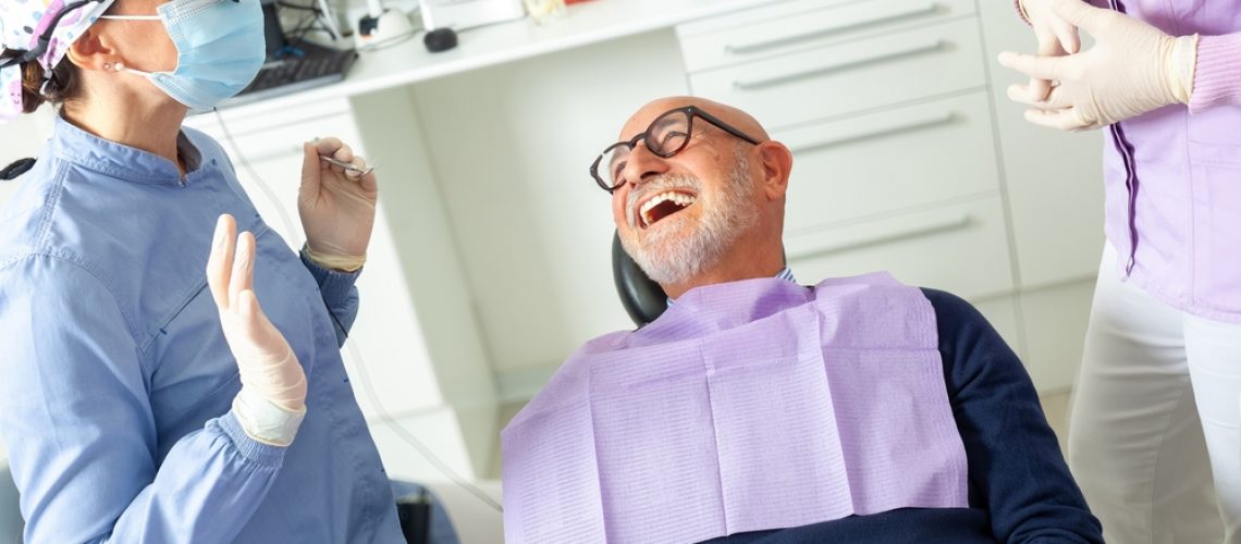 Smiling woman looking in the mirror after receiving her porcelain veneers. No text on image.