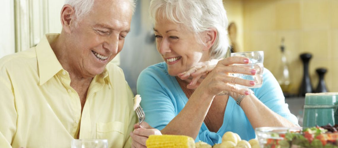 Dental Implant Patients Smiling And Eating Dinner Together