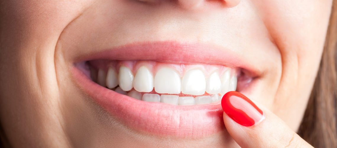 Extreme close up of woman pointing with finger at healthy teeth.